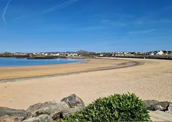 Information card describing Trearddur Bay as a popular sandy beach for families and seaside visits on Anglesey.